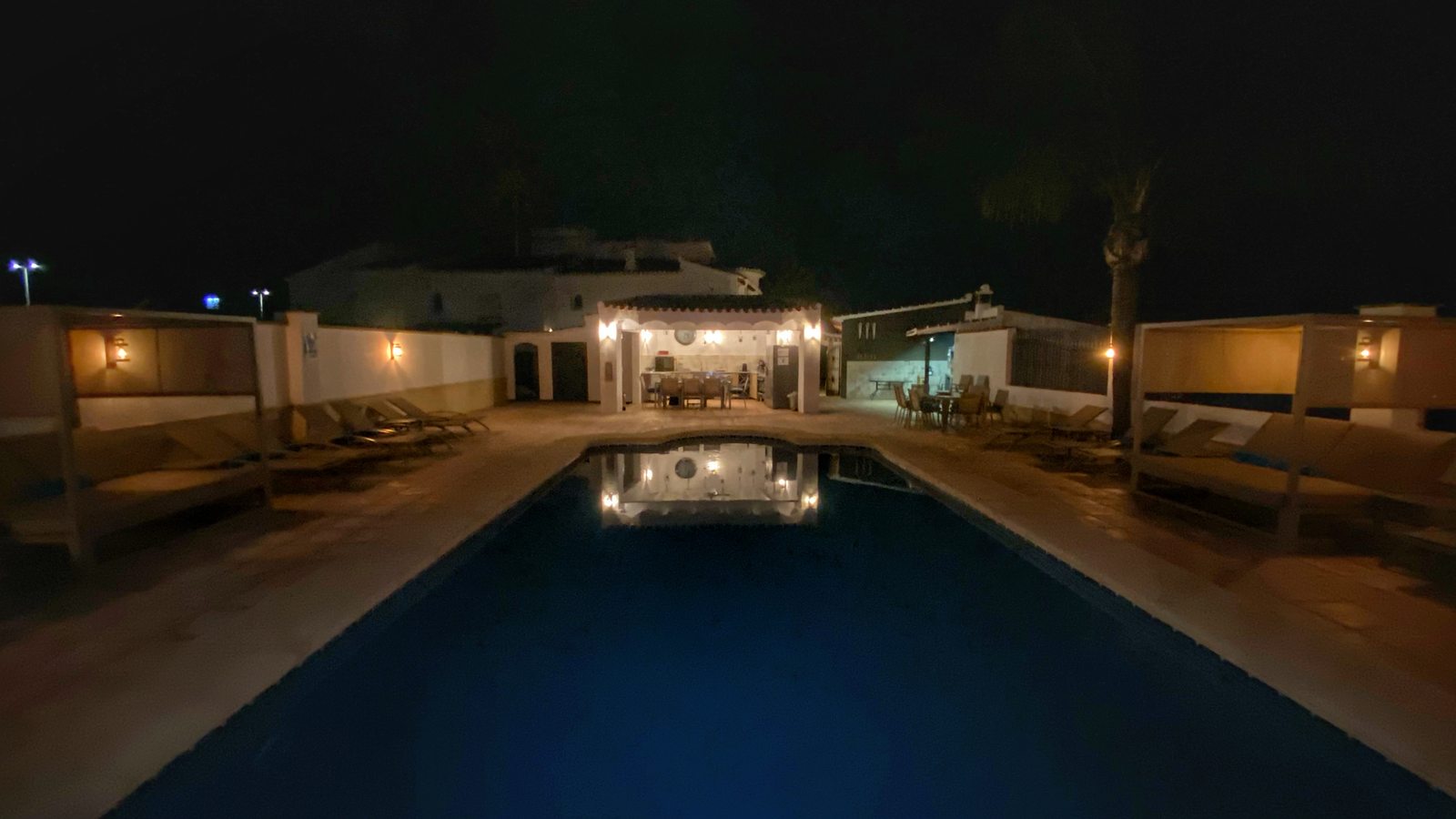 The pool at night, the cabanas lit behind