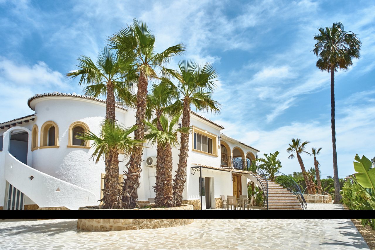 La tour ronde de la villa et les palmiers sous un ciel nuageux