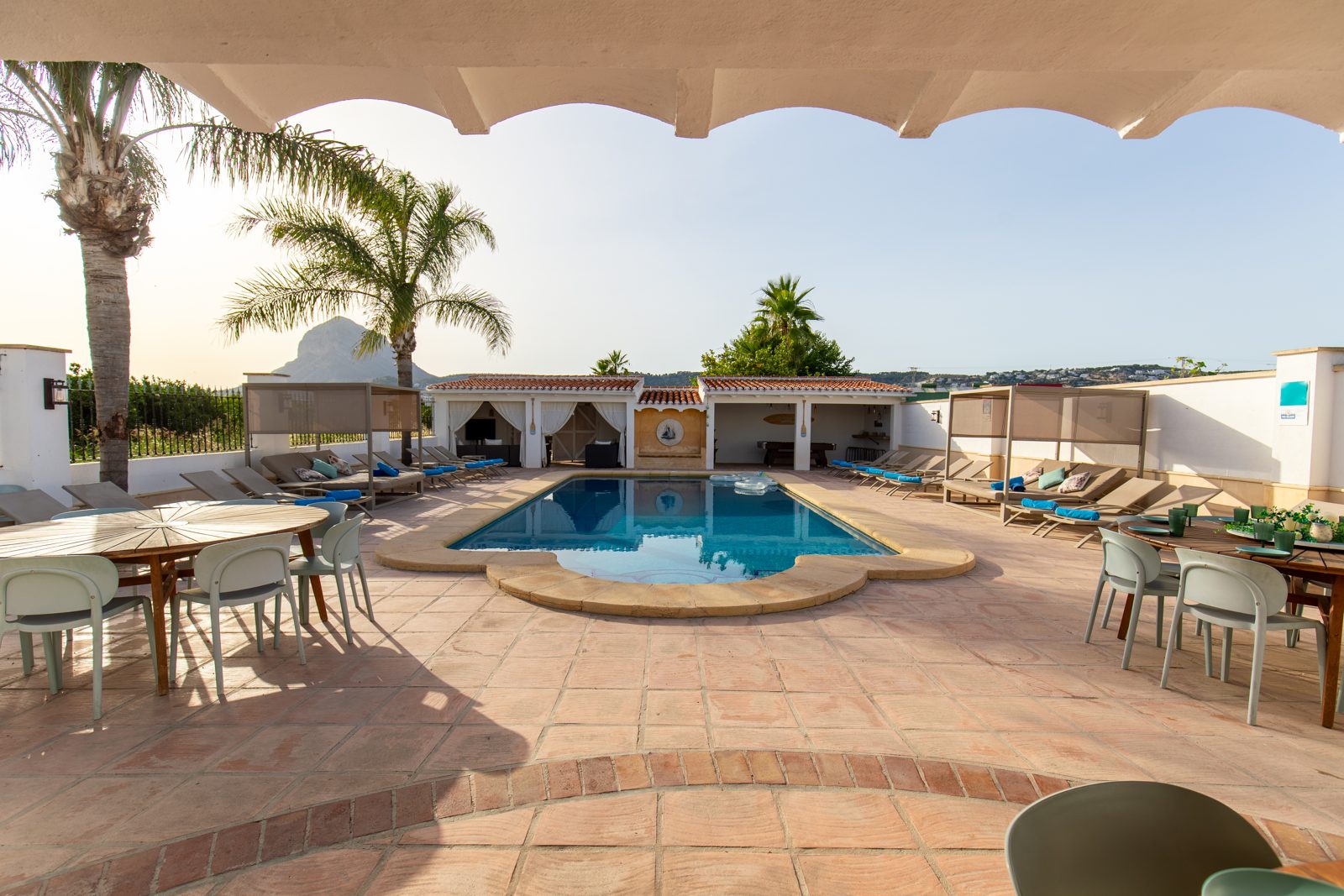 The pool terrace seen from the covered dining area, the Montgó in the distance