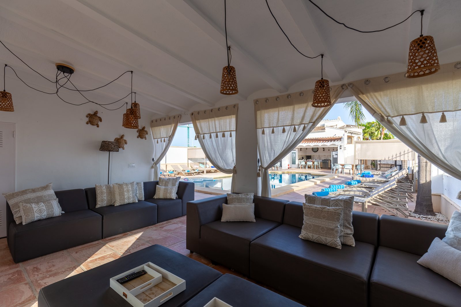 Überdachte Lounge mit großem Ecksofa mit Blick auf den Pool