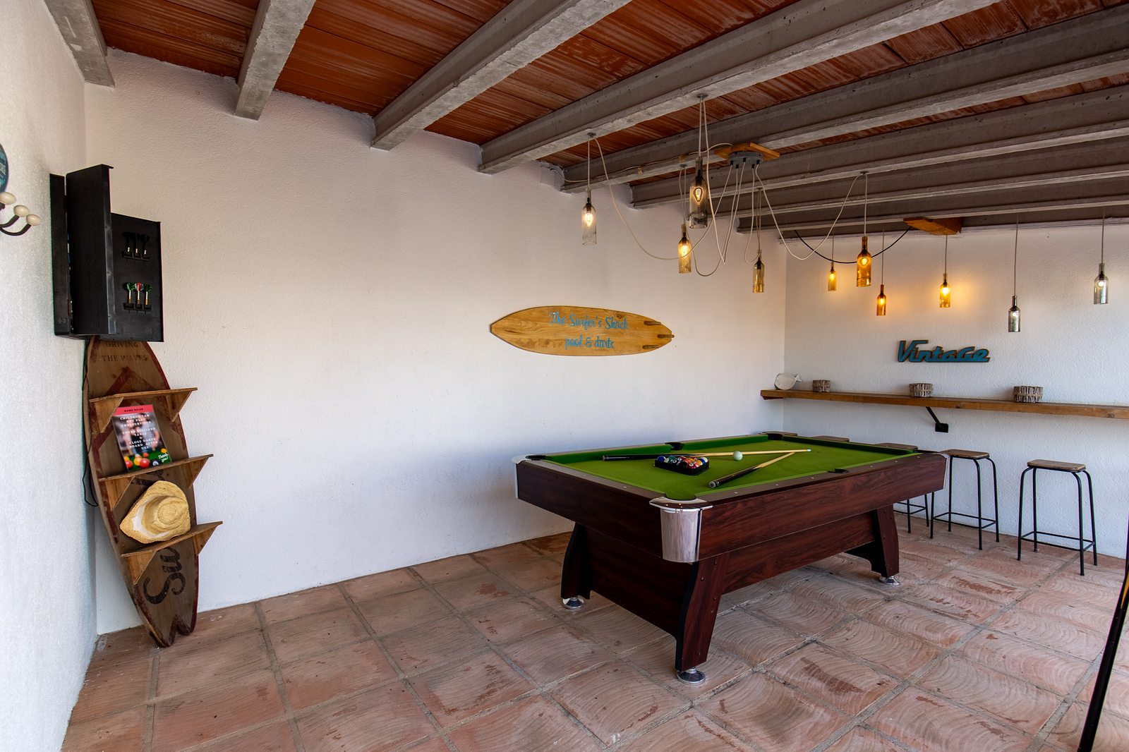 Games room with pool table and surfboards under beamed ceiling