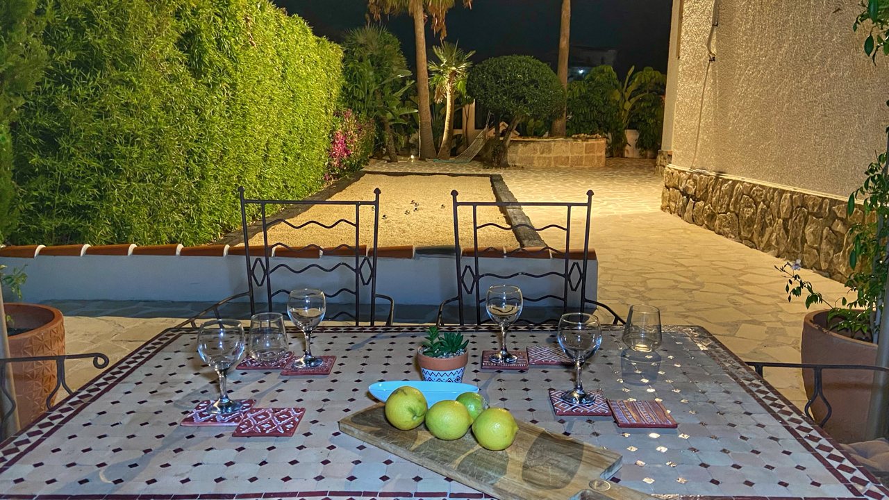 Tiled outdoor table laid at night under garden lighting