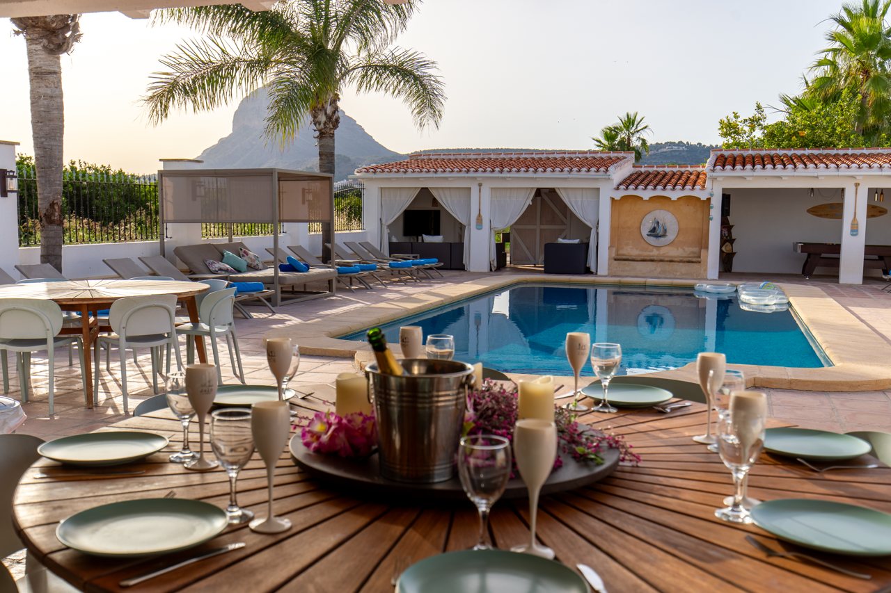 Table laid on the wooden deck with the pool at golden hour
