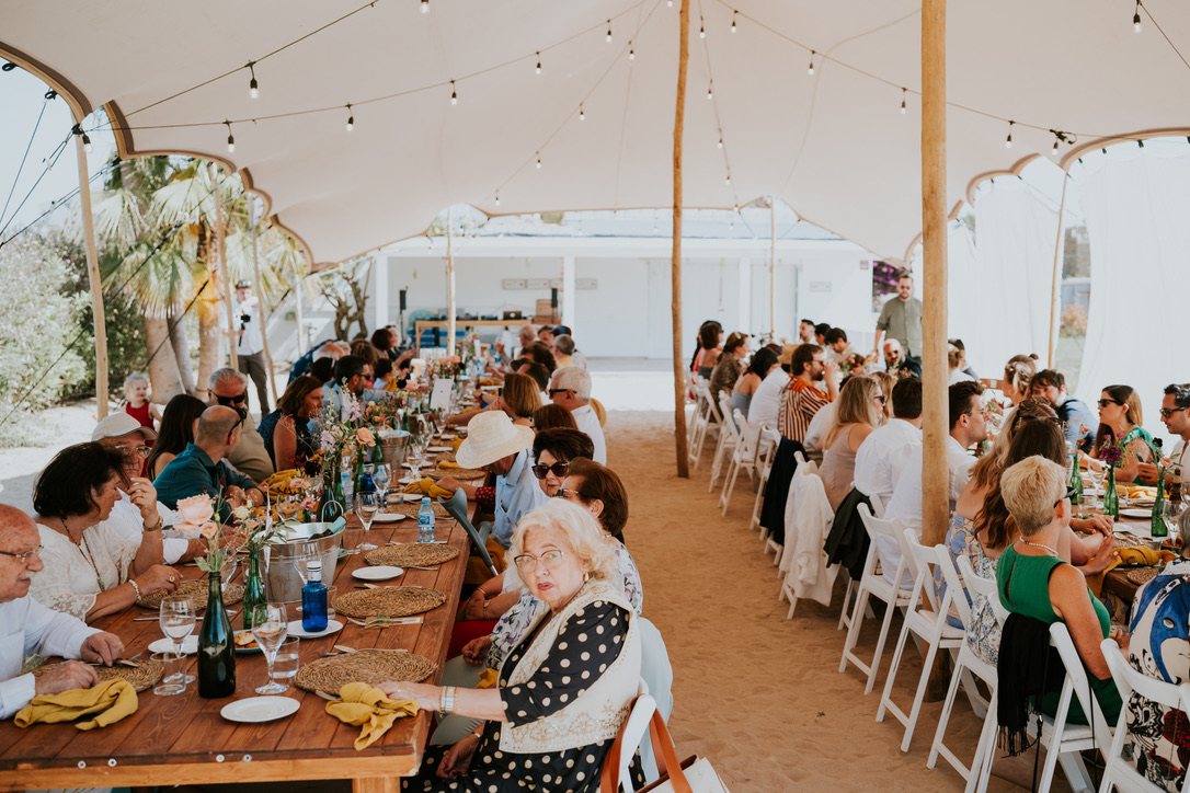 Wedding dinner at long tables under a canopy