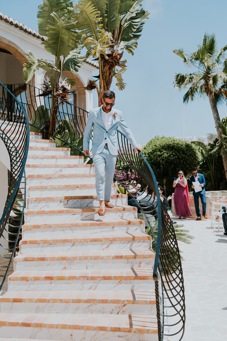 Le marié descendant l'escalier courbe de la villa