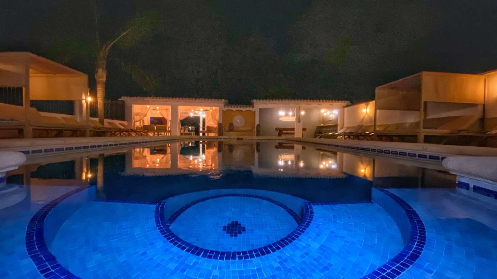 The pool lit up at night with the villa glowing behind