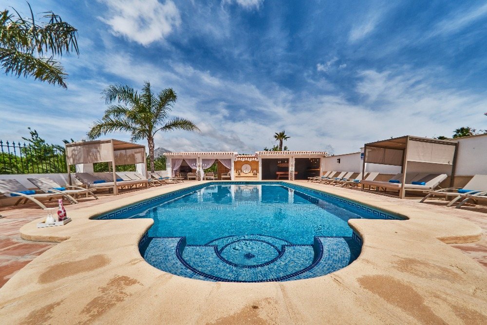 Saltwater pool with sand-coloured surround, cabanas and palms